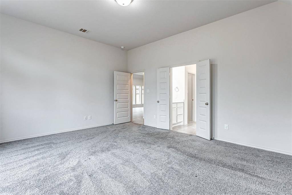 This spacious primary bedroom features double doors leading to an ensuite bathroom.