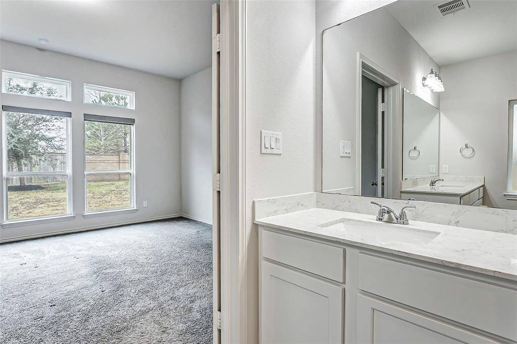 Upon exiting the bathroom notice the bright bedroom with large windows offering natural light and a view of the backyard.
