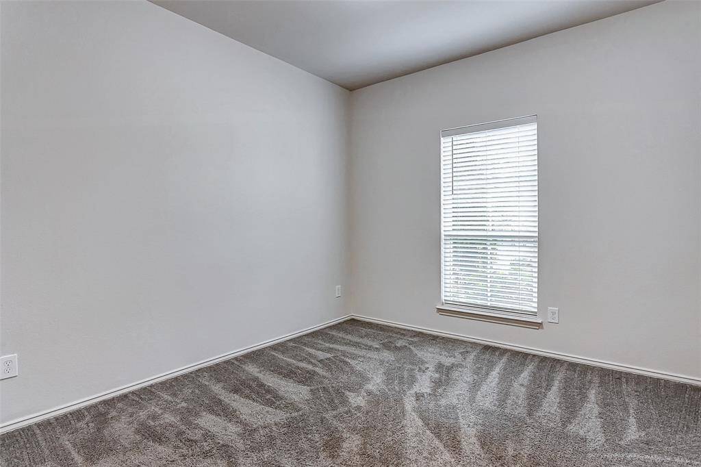 Bright room with neutral walls and plush carpet. A window with blinds allows natural light to fill the space, creating a cozy atmosphere. Ideal for a bedroom or home office.