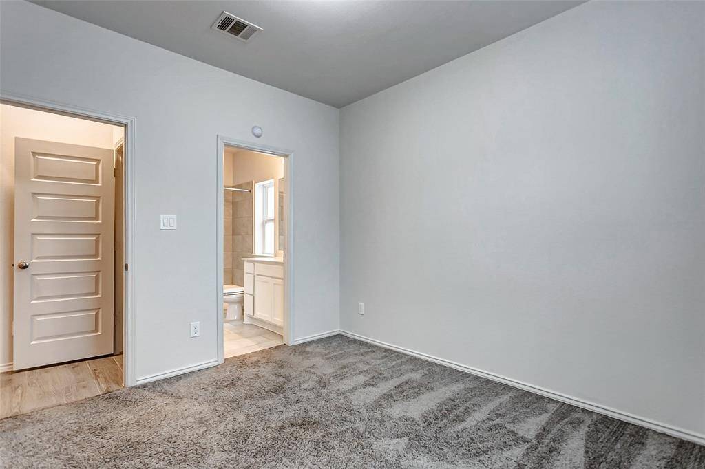 This room features neutral walls and carpet flooring, with an en-suite bathroom.