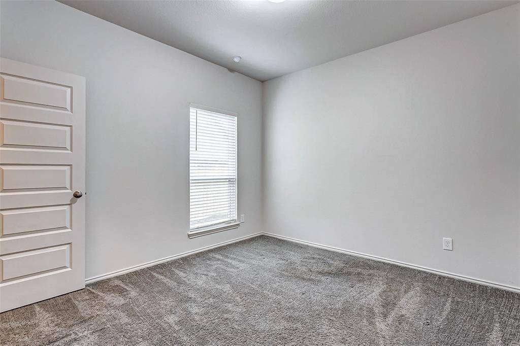 Room features a bright airy window, allowing natural light, and a paneled door. Ideal for a bedroom or office space.