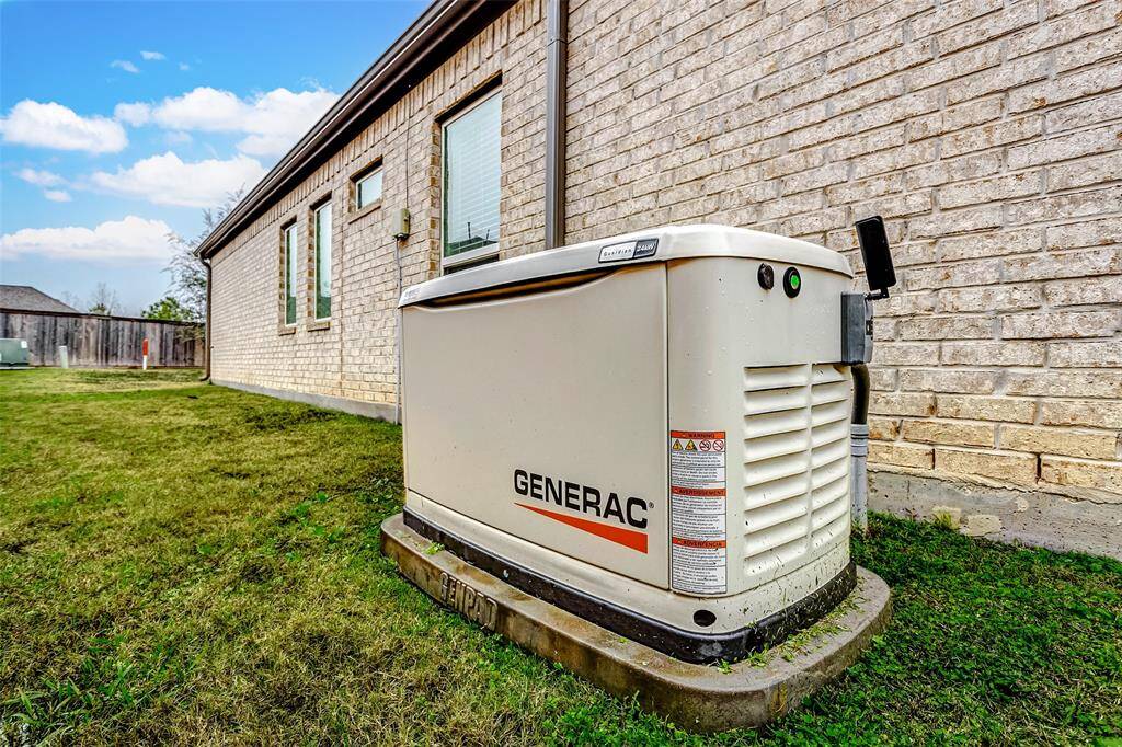 The side of house featuring a Generac backup generator installed on a concrete pad.