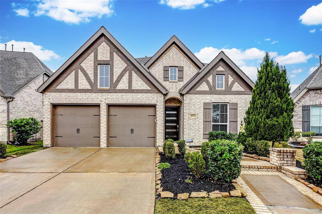 Tour this charming home, which features a Tudor-style exterior with a brick facade and two-car garage. The manicured lawn and landscaped garden add curb appeal, while the gabled roof and decorative woodwork provide a classic touch.