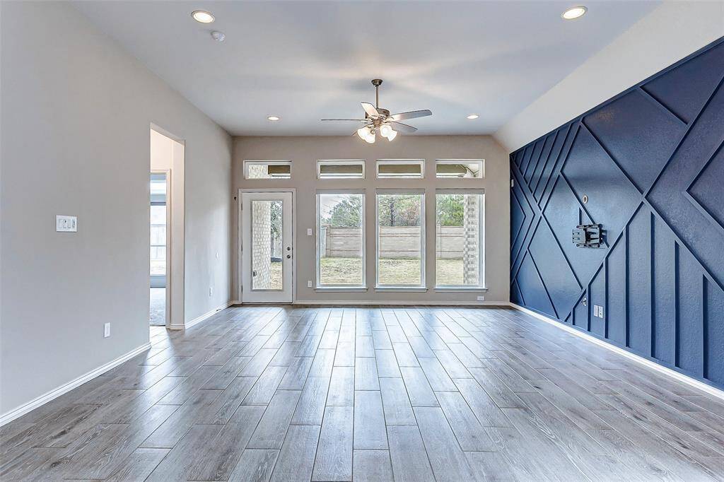 Notice the large windows and a glass door leading to the backyard. A ceiling fan and recessed lighting add to its modern appeal.