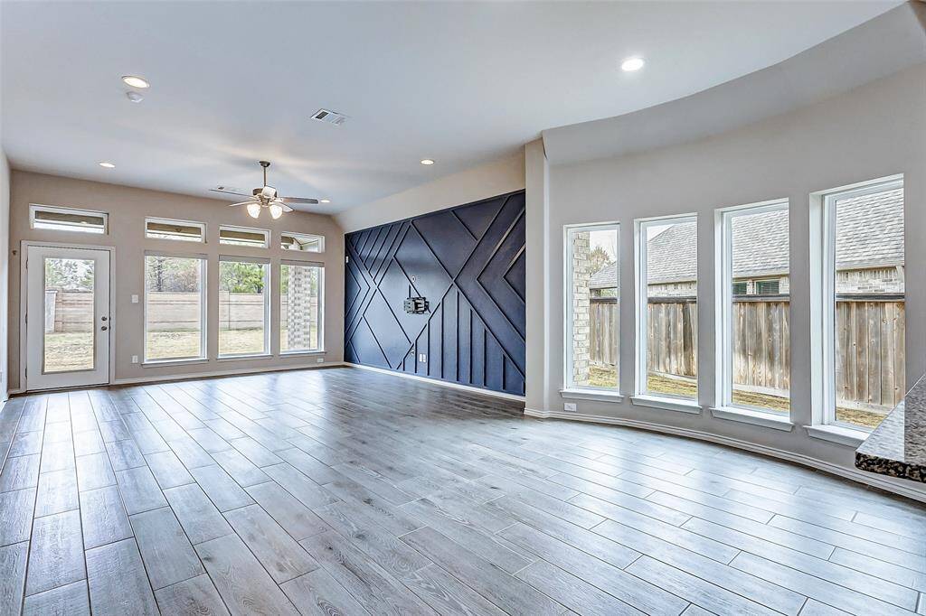 The room is open and airy, ideal for entertaining or relaxing. The curved wall of windows leads to the kitchen.