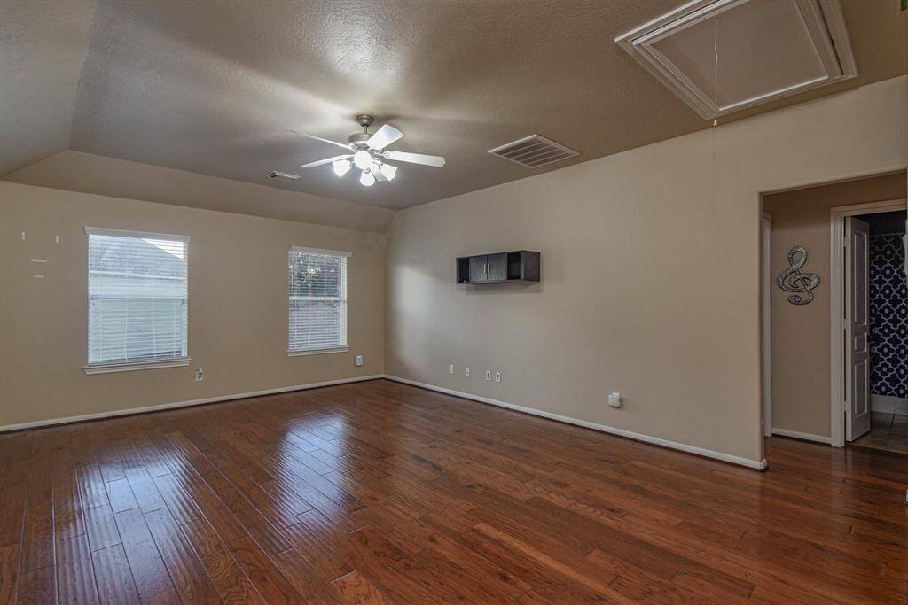 Spacious and inviting game room with elegant wood flooring and ample natural light, perfect for entertainment and relaxation.