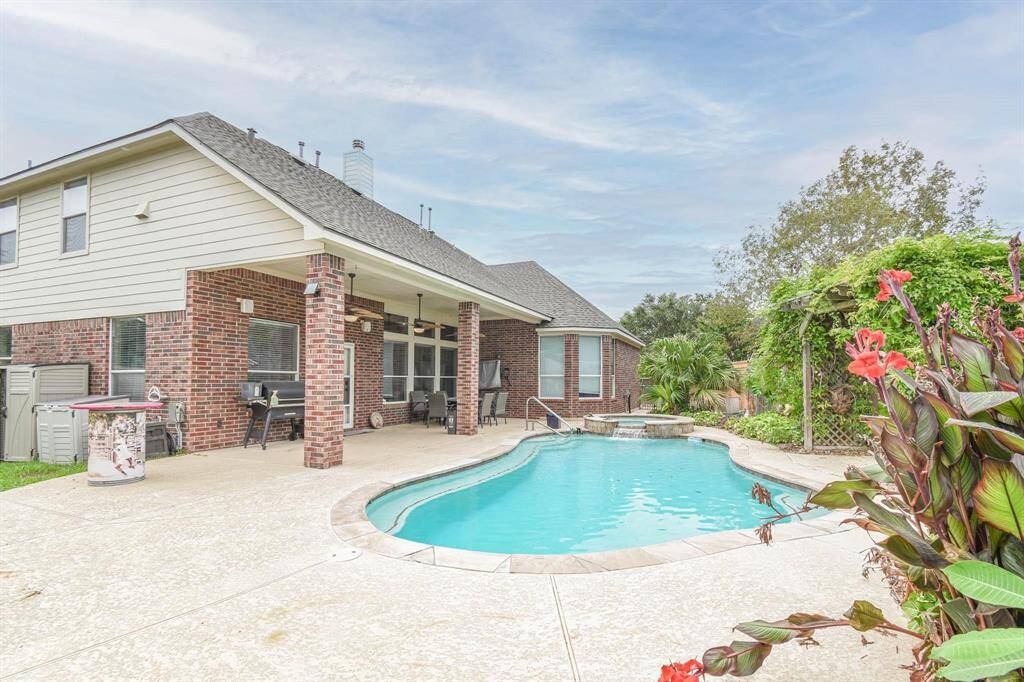 This home features a spacious backyard with a beautiful in-ground pool, a covered patio area, and lush landscaping, perfect for outdoor entertaining and relaxation.