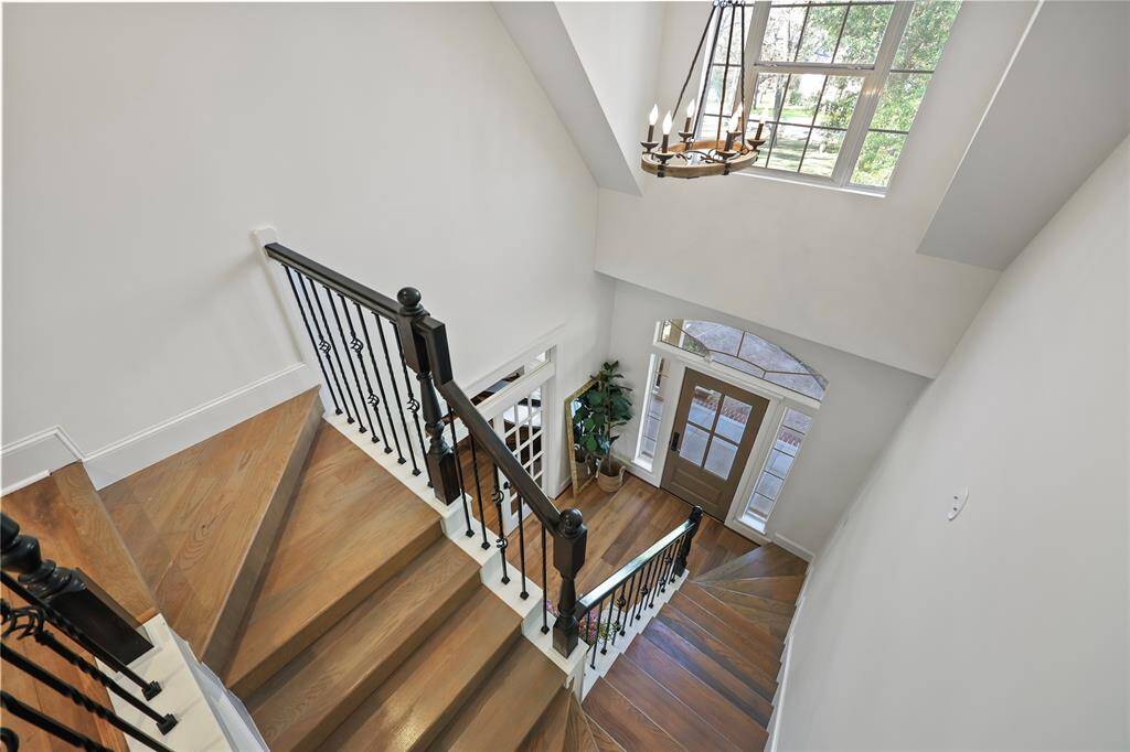View from the upstairs landing showing the semi spiral wooden staircase with black wrought iron spindles leading to the front entrance of the home