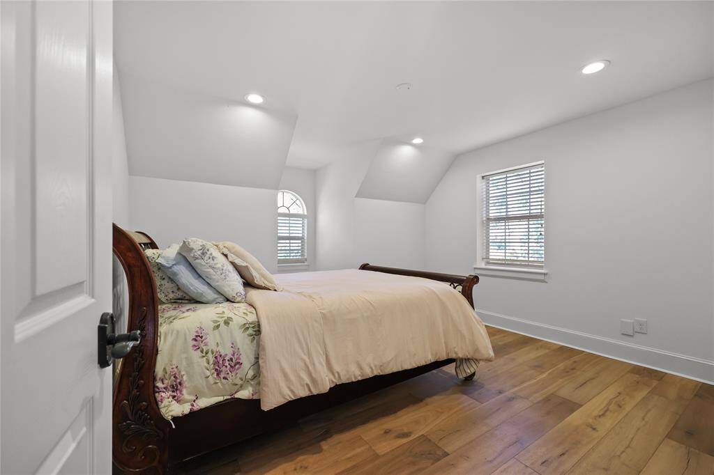 Secondary bedroom with the warm toned wood floor, recessed lighting and oversized molding surrounding the room.