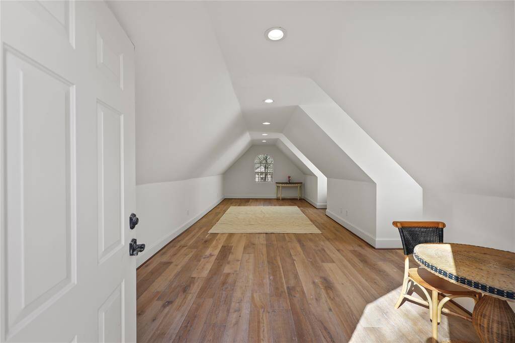 A spacious bonus room above the garage featuring sloped ceilings, recessed lighting, and warm hardwood floors. This room is a versatile area for a home office, playroom, or guest suite