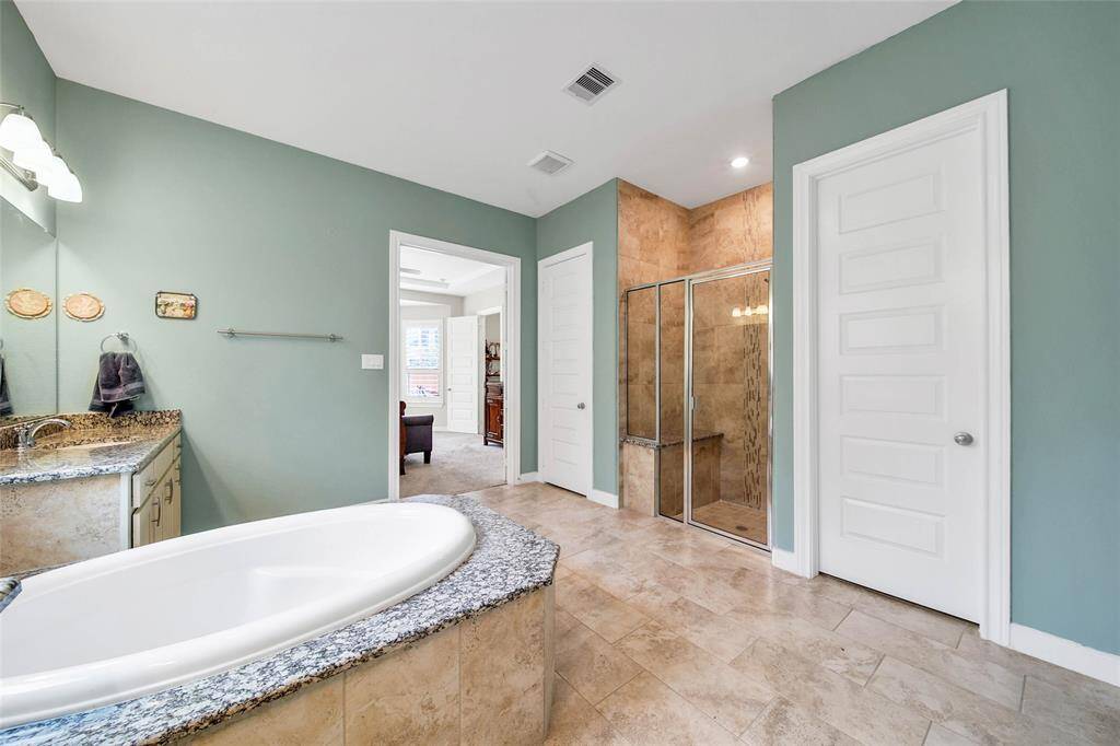 A glass shower with a bench seat, linen closet, and large walk-in closet complete the suite.
