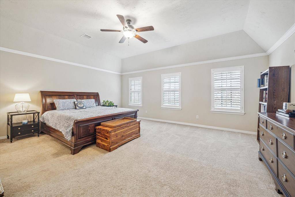 The spacious primary bedroom, located on the second floor, features a vaulted ceiling, plantation shutters, and a ceillng fan.