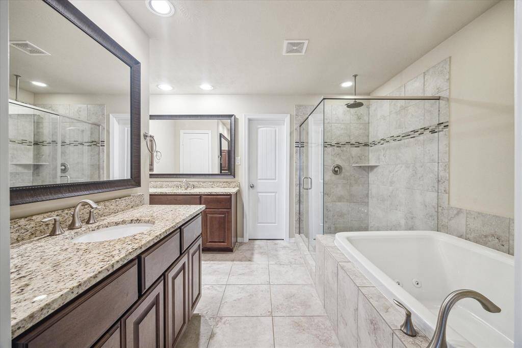 The primary bathroom features dual vanities with granite countertops, a jetted tub, a separate shower, and a spacious closet with built-in shelving.