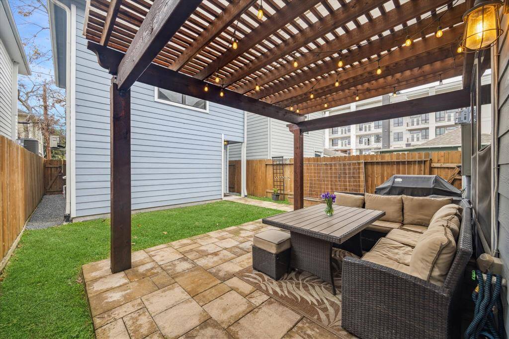 The fully fenced backyard features a covered patio, pergola, and lawn, creating a peaceful retreat for outdoor living.