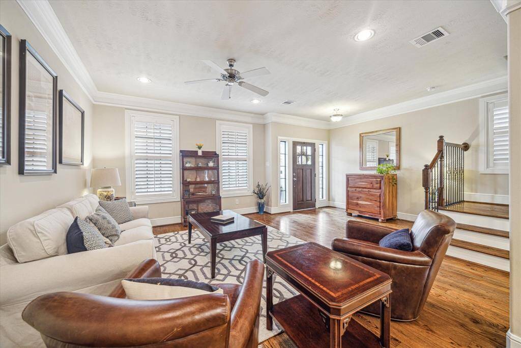 The living room features custom plantation shutters, tall ceilings, double crown molding, and beautiful hardwood floors.