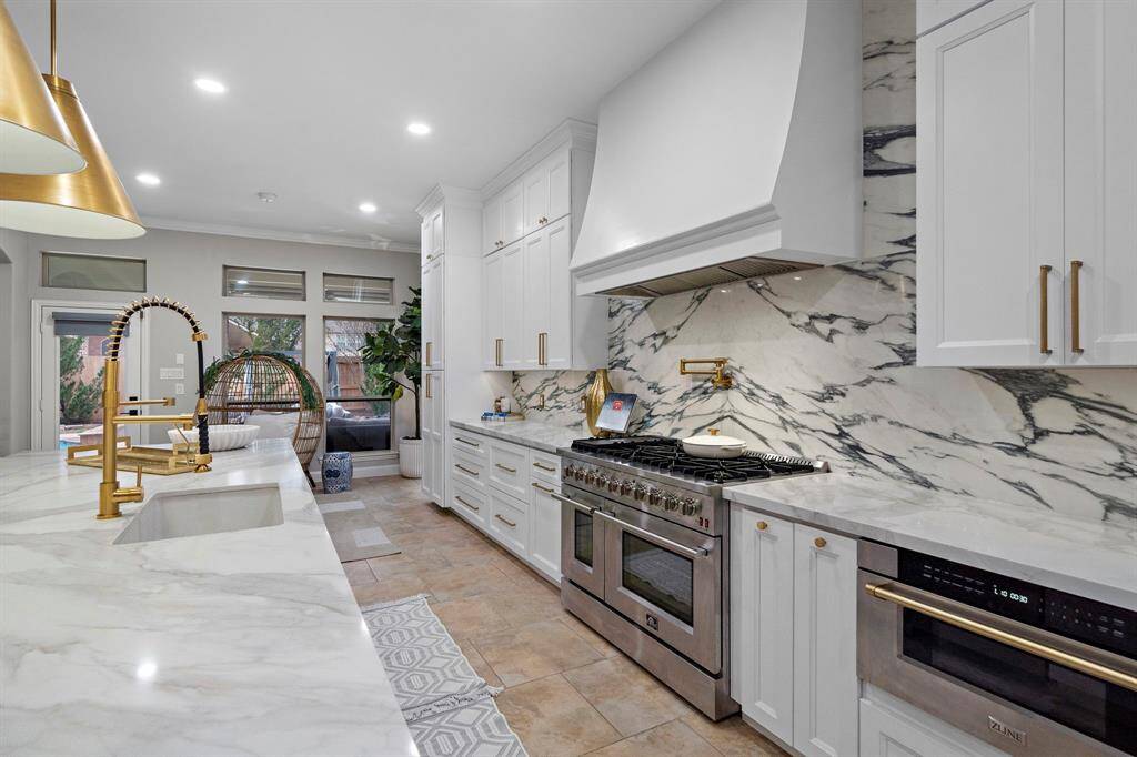 A true highlight of the space is the porcelain backsplash, paired with high-end Buster + Punch outlets for a touch of sophistication. The oversized 24-inch drum lighting adds an elegant pop, enhancing the kitchen’s luxurious feel.
