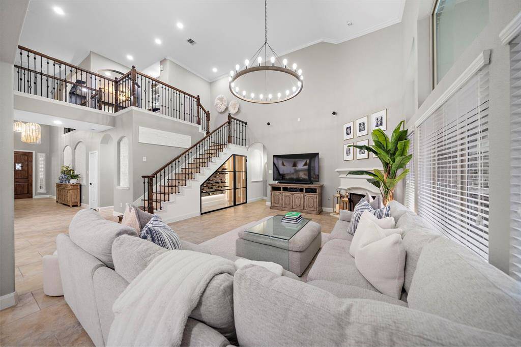 Enjoy a seamless flow into the grand living room with sky-high ceilings, updated custom lighting and a cozy gas fireplace complete with a wall of windows allowing for natural lighting to shine through.
