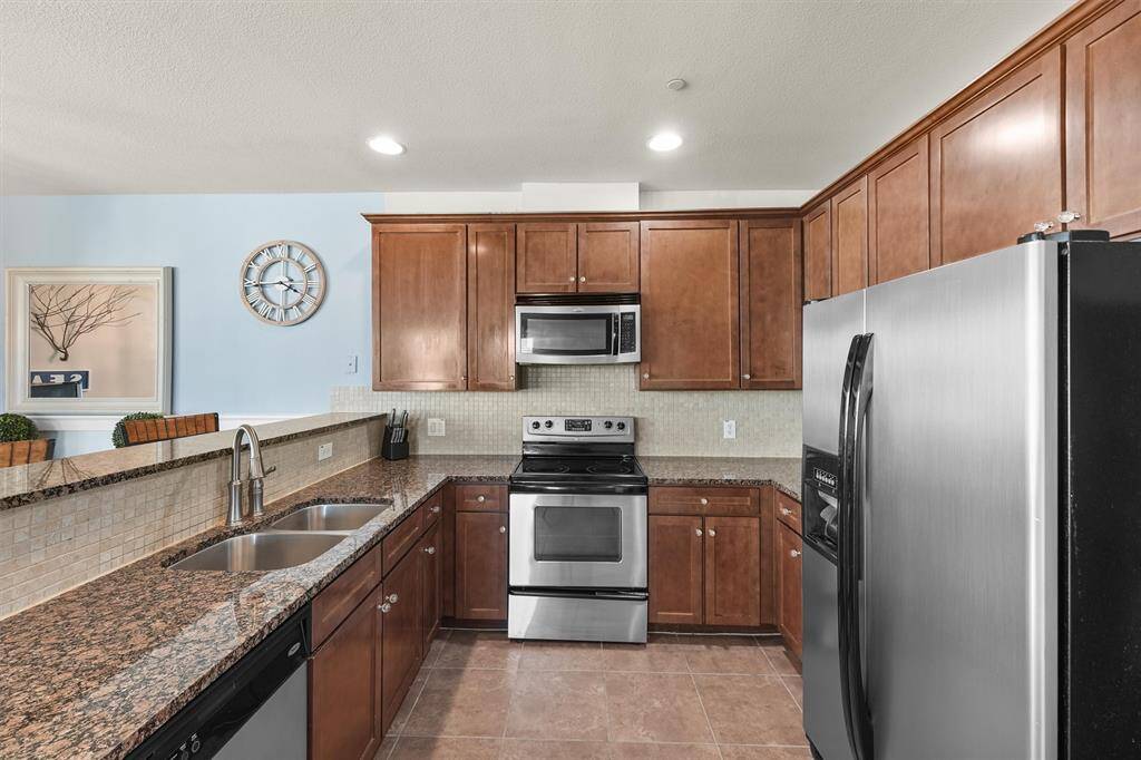 Another perspective of the kitchen captures the detailed tile backsplash, which adds both functionality and elegance. The modern design is complemented by a mix of natural light and recessed lighting, ensuring a bright and welcoming atmosphere.