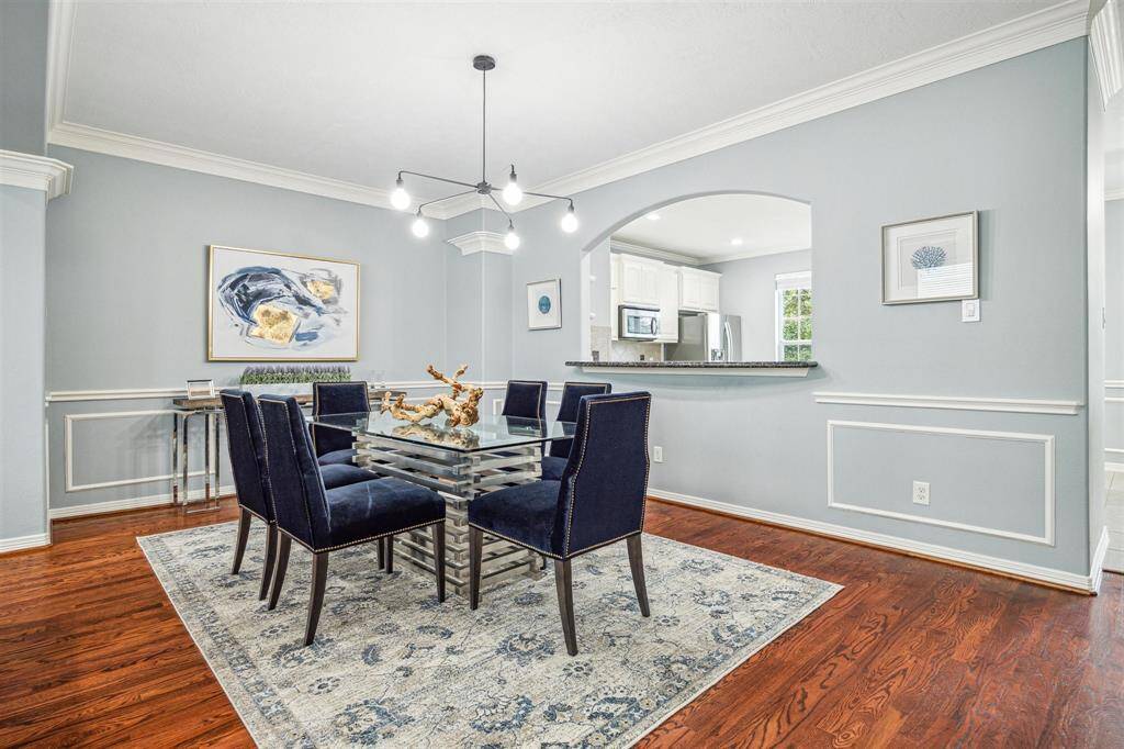 Dining room with hardwood floors, modern light fixture, and crown molding.