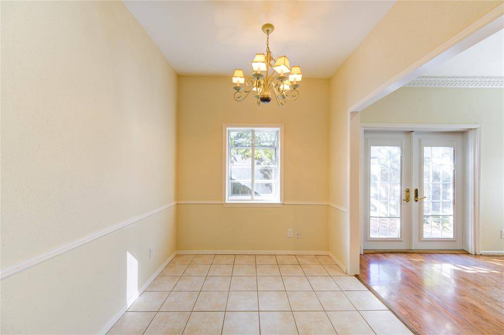 Bright breakfast space with tiled flooring, a charming chandelier, and a garden window. Opens to the family room with French doors and engineered wood floors, offering abundant natural light.