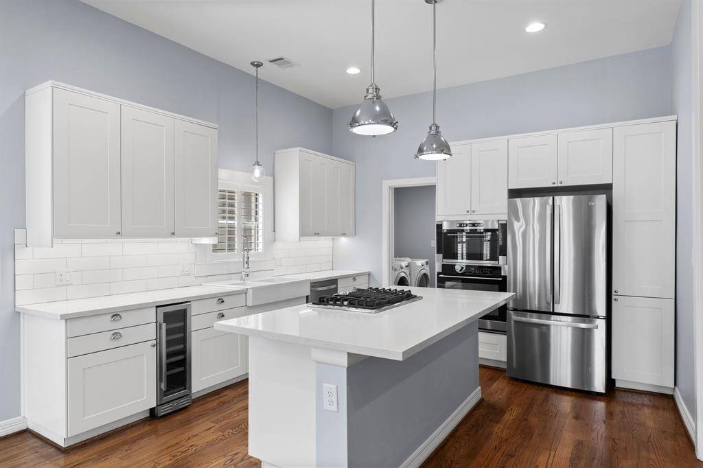 Island kitchen with soft closing drawers, built in wine fridge and gas range.