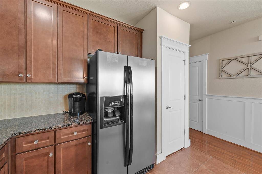 This angle of the kitchen shows the efficient layout and the transition to the foyer and hall. The stainless steel refrigerator is conveniently located next to the pantry, offering easy access to ingredients and kitchen essentials.