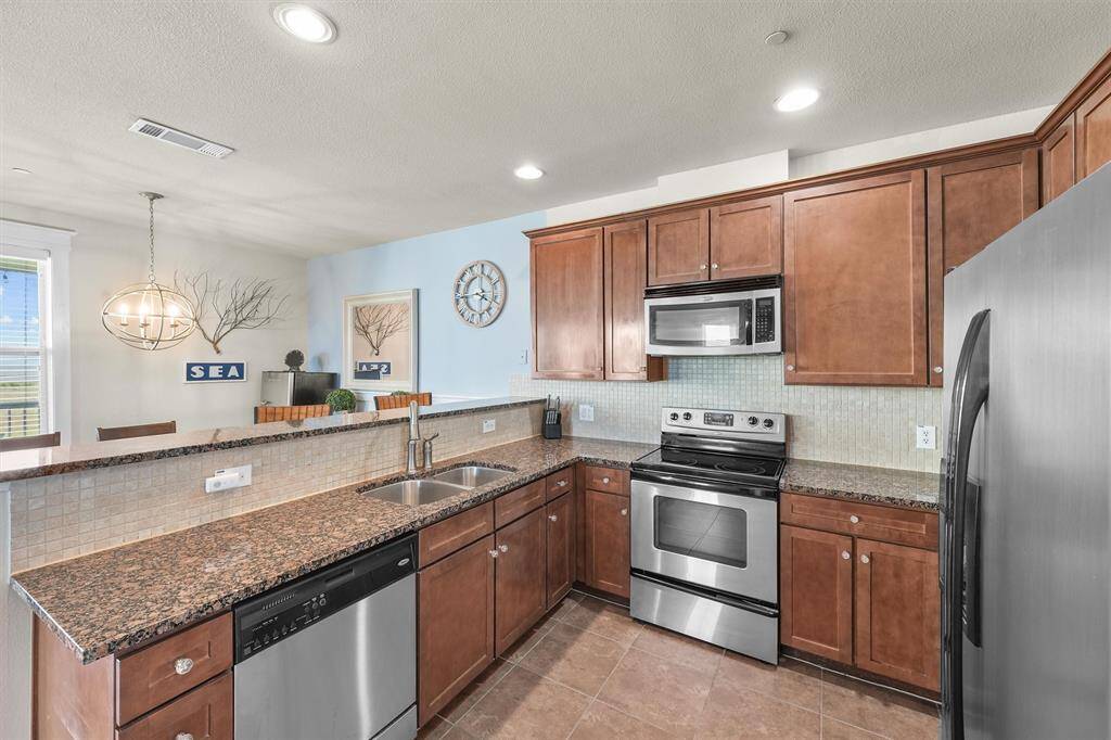 A view of the kitchen highlights the stainless steel appliances and ample countertop space. The open layout connects seamlessly to the dining area, enhancing the flow of the home and making it ideal for hosting gatherings.