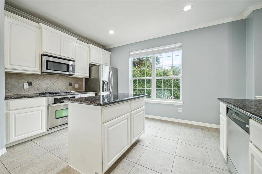 Freshly painted island kitchen with tile floors, recessed lighting, and crown molding.