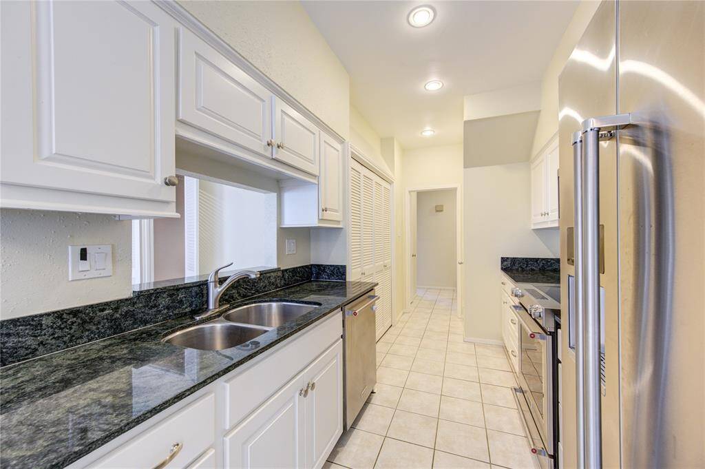 Sleek white kitchen featuring stainless steel appliances and elegant granite countertops.