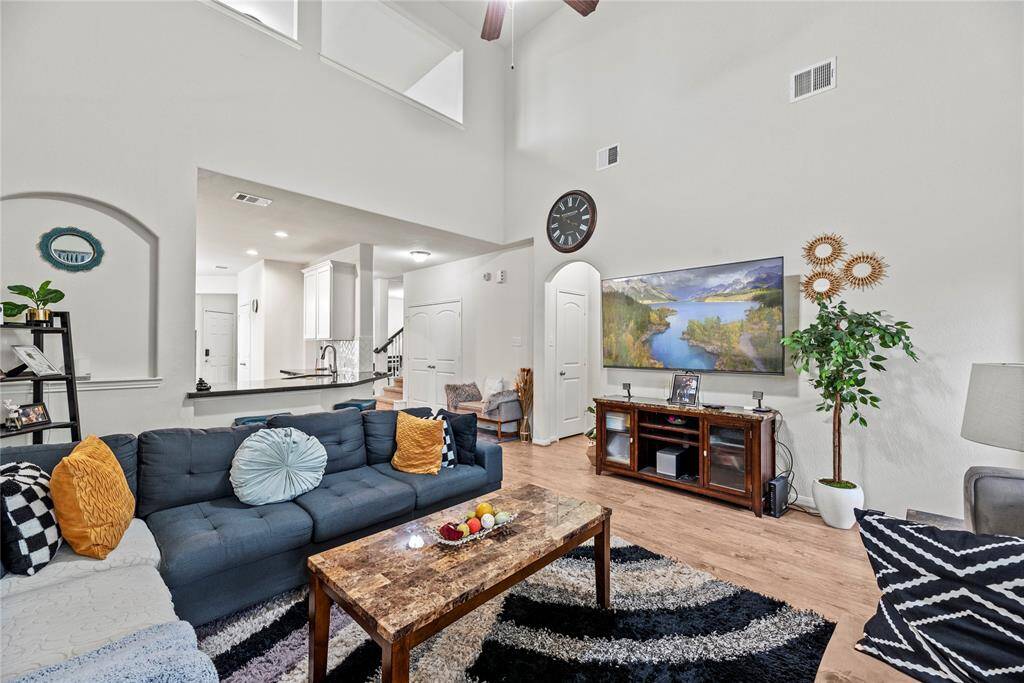 Sun-drenched living space with dramatic two-story ceilings, sleek wood-like vinyl planks, and tons of charm.