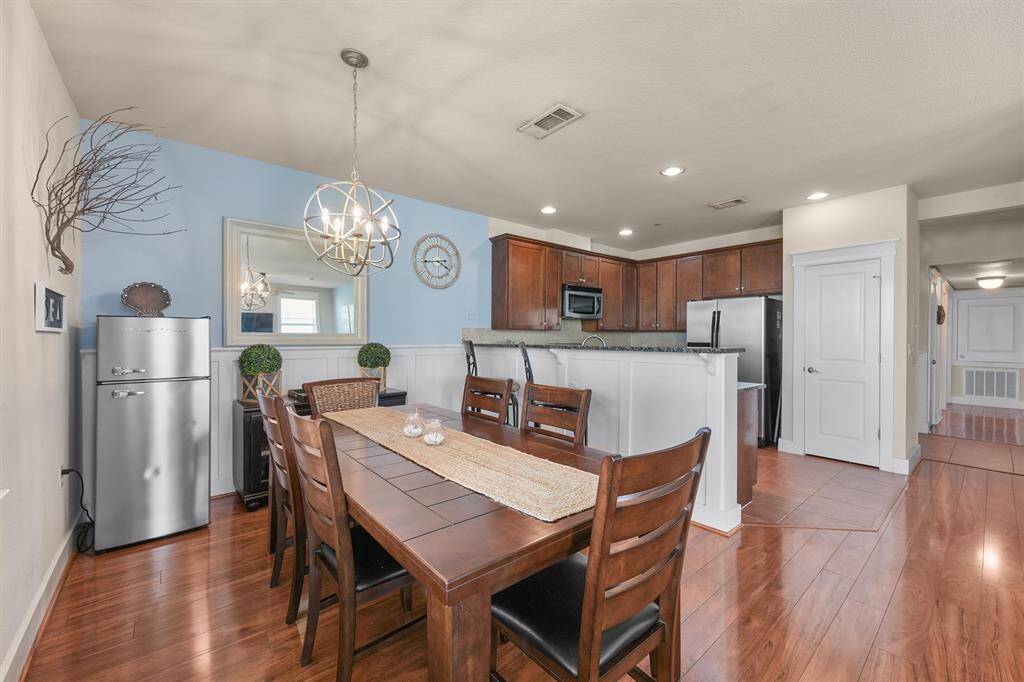 The dining room offers an open layout, seamlessly connecting to the kitchen and living room. The space is brightened by natural light from large windows and features a stylish chandelier that adds a touch of elegance.