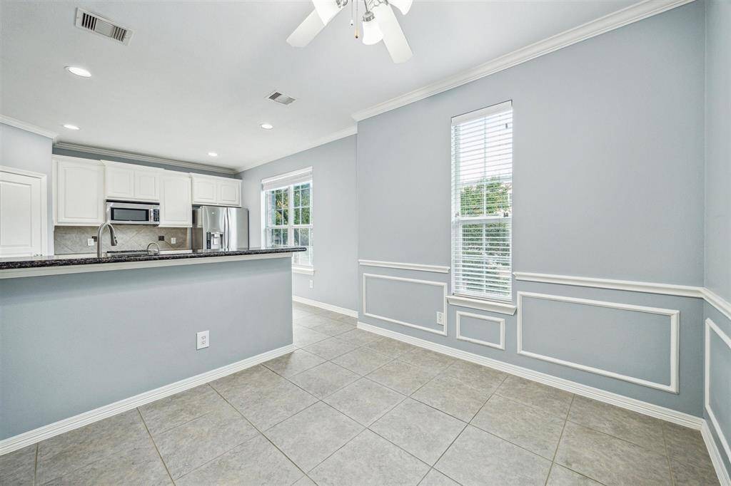 Breakfast room with tile floors, ceiling fan with lights, crown molding and wainscoting.
