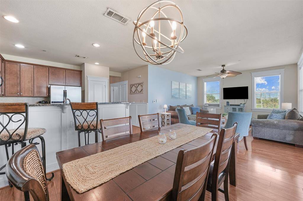 The dining area, with its rustic wooden table and contemporary lighting fixture, provides a cozy space for meals and gatherings. The open design allows easy access to the kitchen and living room, enhancing the home's flow and functionality.