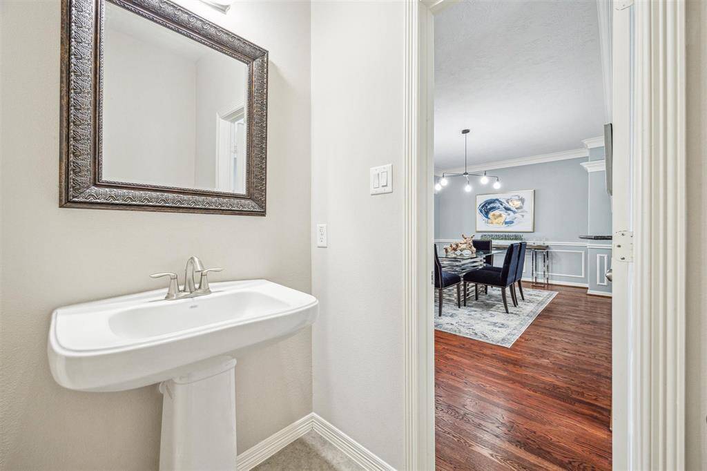 Second floor powder bath with tile floors, pedestal sink, and sconce lighting.