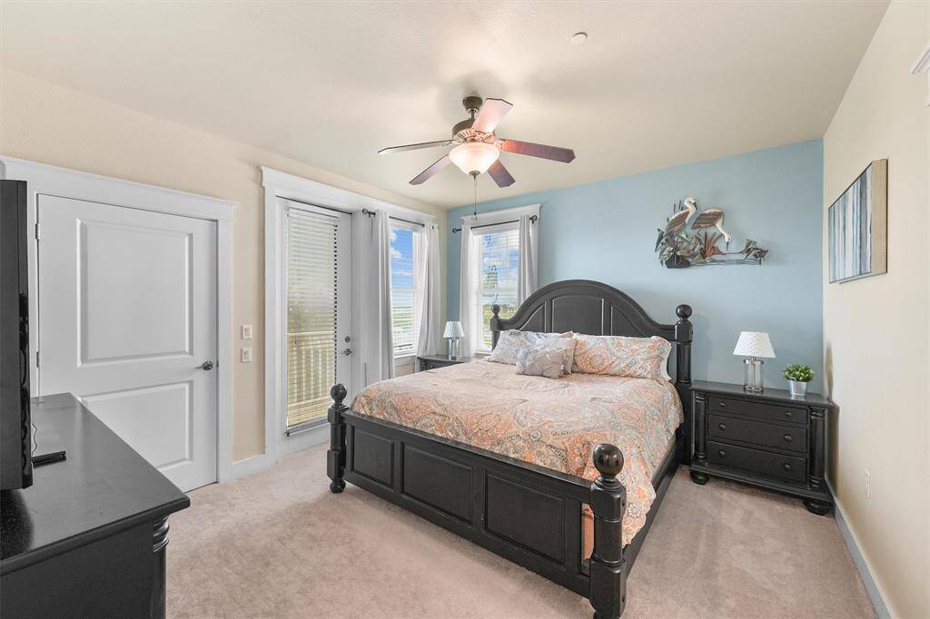 The primary bedroom is a tranquil retreat featuring a king-sized bed with an elegant headboard and matching bedside tables. A glass door and windows let in plenty of natural light and provide access to a private balcony, enhancing the room's airy feel.