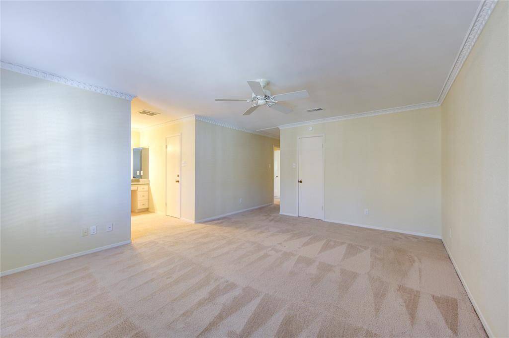 Spacious primary bedroom with soft carpet, crown molding, and an ensuite bath for ultimate comfort and style.