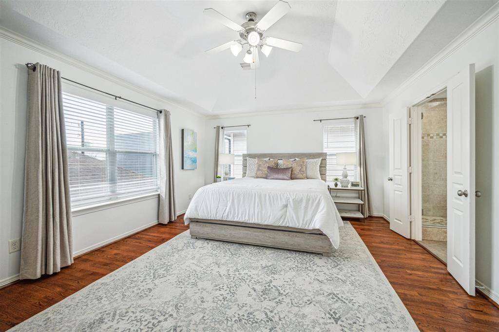 The primary suite is bathed in natural light and features a raised ceiling, as well as a generously sized bathroom with split vanities, a soaking tub, shower, and walk-in closet.