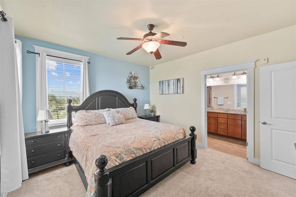 Another view of the primary bedroom shows its spacious layout, with the king-sized bed positioned against a soft blue accent wall. The room leads directly into a well-appointed en-suite bathroom, offering convenience and privacy.