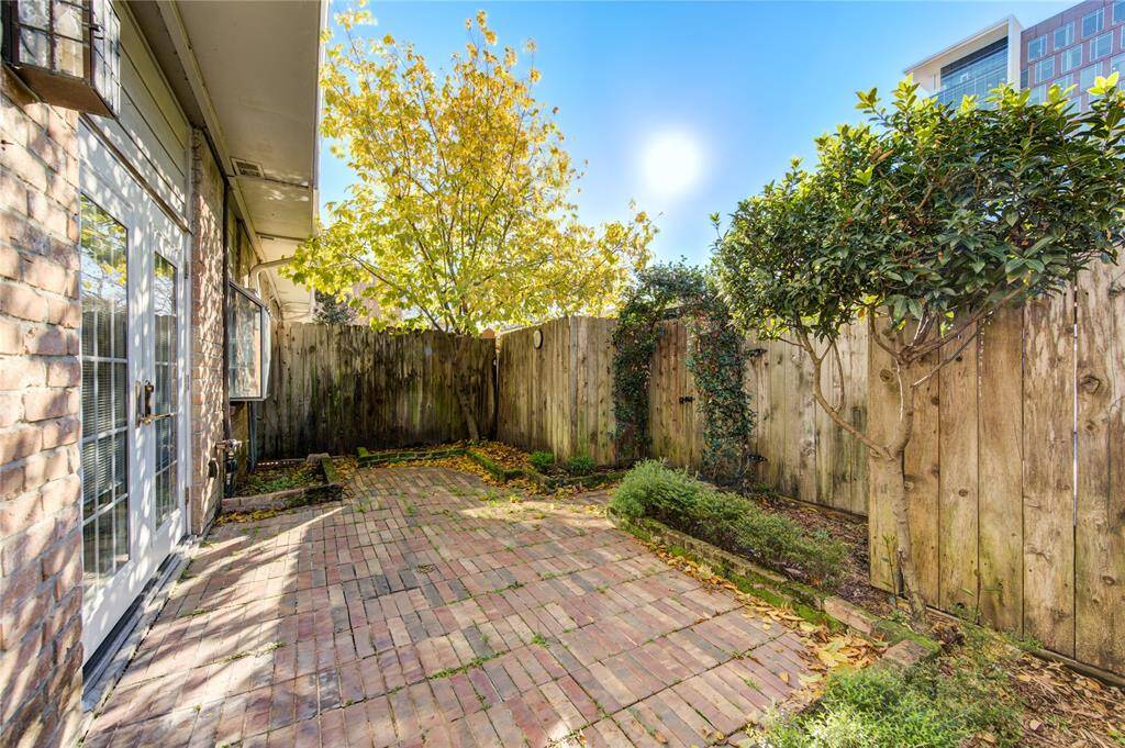 This charming backyard features a brick patio, privacy fence, and mature trees, offering a cozy outdoor retreat.