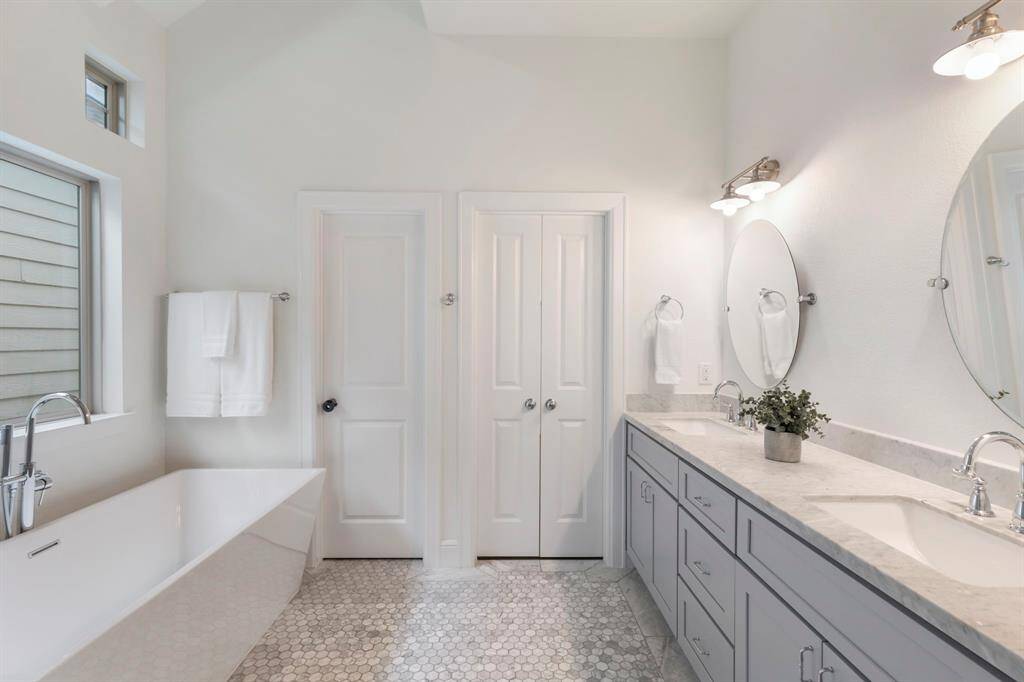 A luxurious, spa-like primary bathroom featuring double sinks and a relaxing soaking tub.