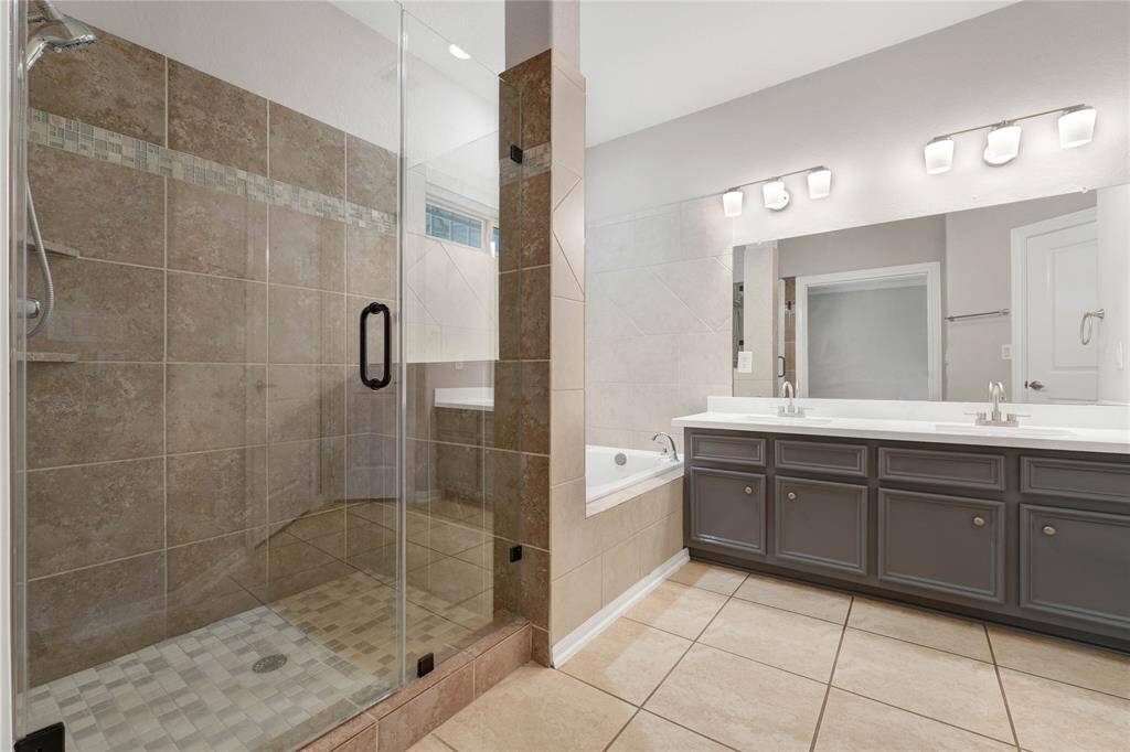 beautiful primary bath with quartz countertops soaking tub and extended standup shower.