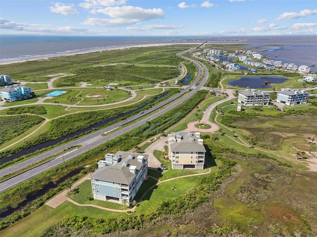 An aerial shot capturing the serene setting of the Pointe West community with its picturesque buildings and the inviting community amenities. The surrounding greenery and water bodies add to the tranquil atmosphere.