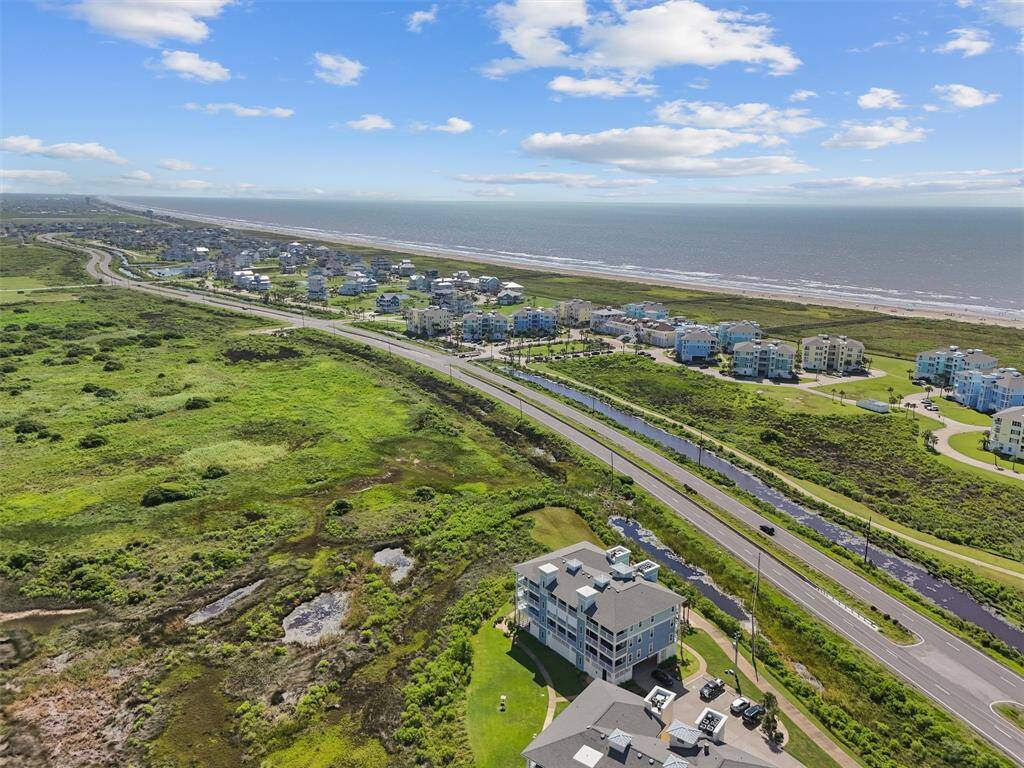 This aerial perspective highlights the proximity of the Pointe West community to the beach. The expansive view includes the ocean, a community pool, and the beautifully maintained grounds.