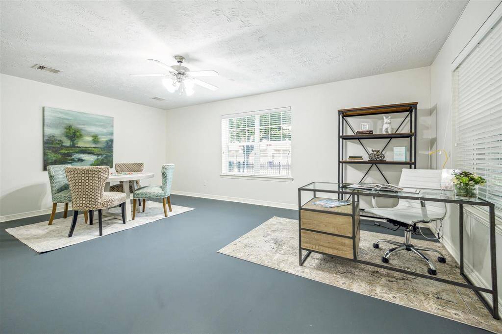 First-floor secondary bedroom with concrete floors, ceiling fan with lights, windows with blinds, and is en suite.