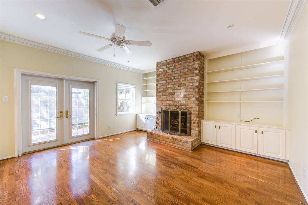 Cozy family room featuring a brick fireplace, complemented by built-in bookshelves and cabinets with access to the backyard