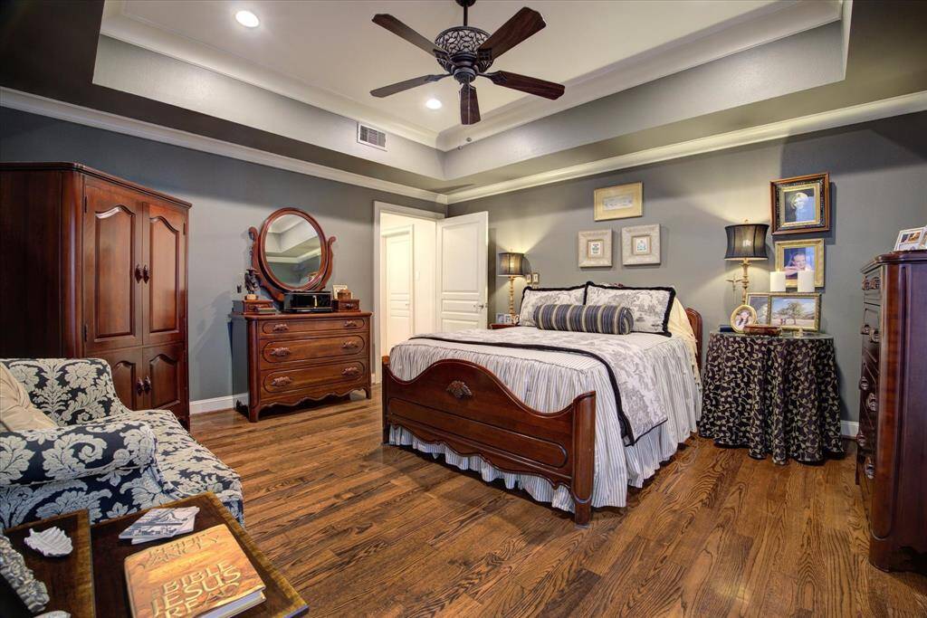 Oversized primary bedroom with vaulted ceiling and hardwood floors.