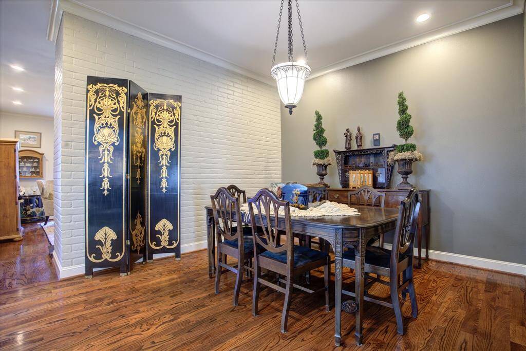 This gracious dining room with hard wood flooring and brick wall is in the center of the home.