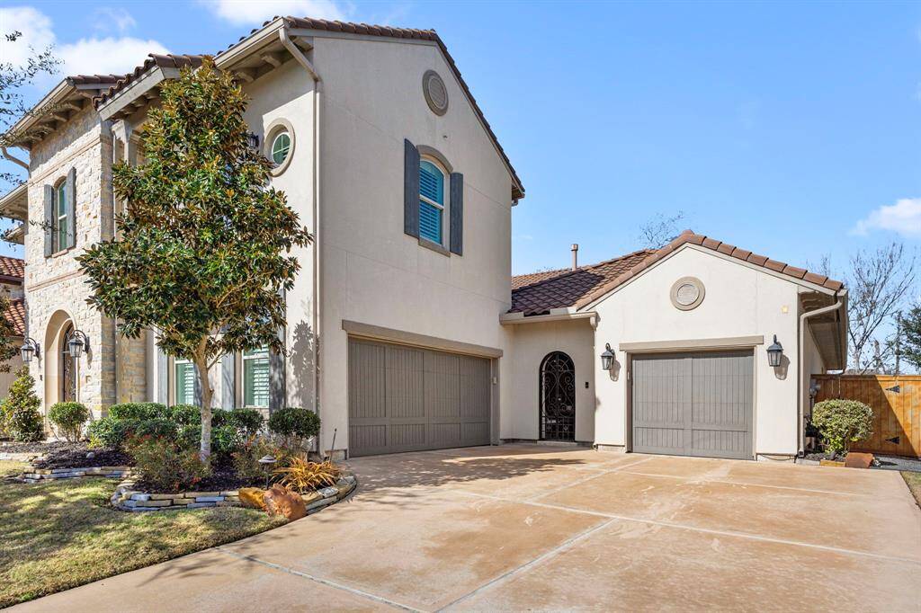 This elegant two-story home features a stucco and stone exterior, a spacious three-car garage, and a well-maintained driveway. The property is accentuated by a landscaped front yard with mature trees and shrubs, creating a welcoming curb appeal.