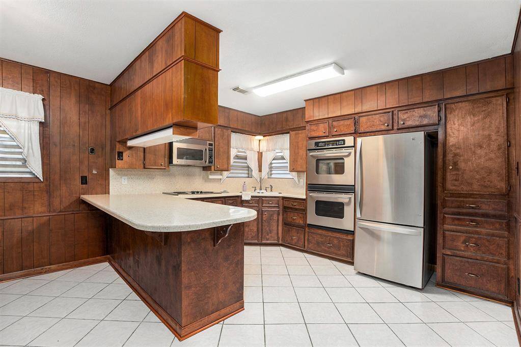 Spacious kitchen with double ovens, cooktop, and charming corner window—ideal for culinary enthusiasts.