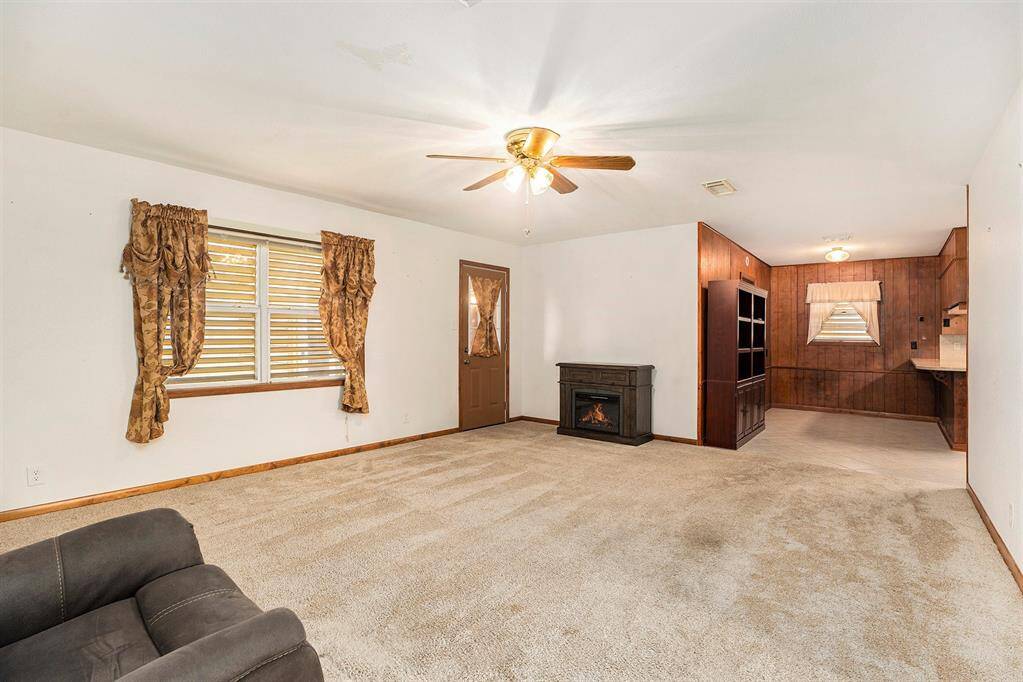 Cozy living area with warm carpeting, inviting natural light, and a stylish ceiling fan. Perfect for relaxation and entertaining.